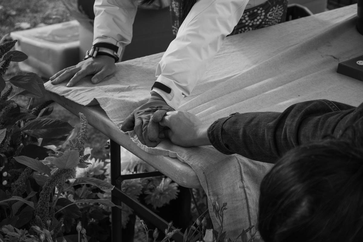 Hands of Sylvia and her friend place a table cloth.